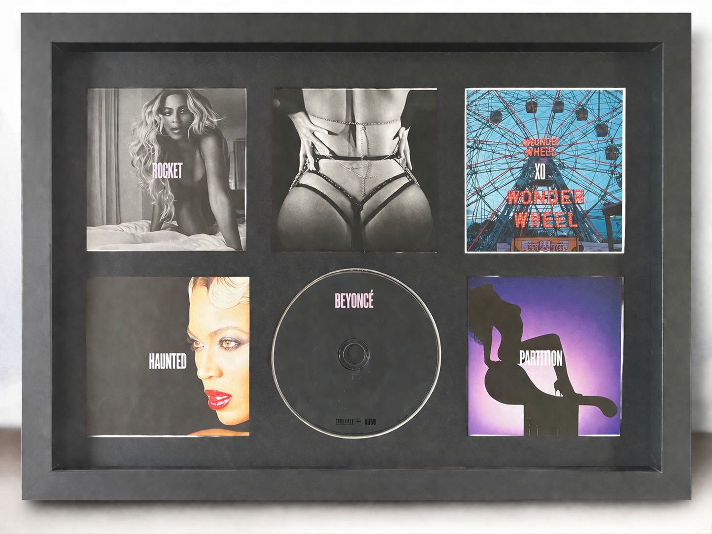 Framed collage of Beyoncé album covers and a CD with 'Beyoncé' branding.