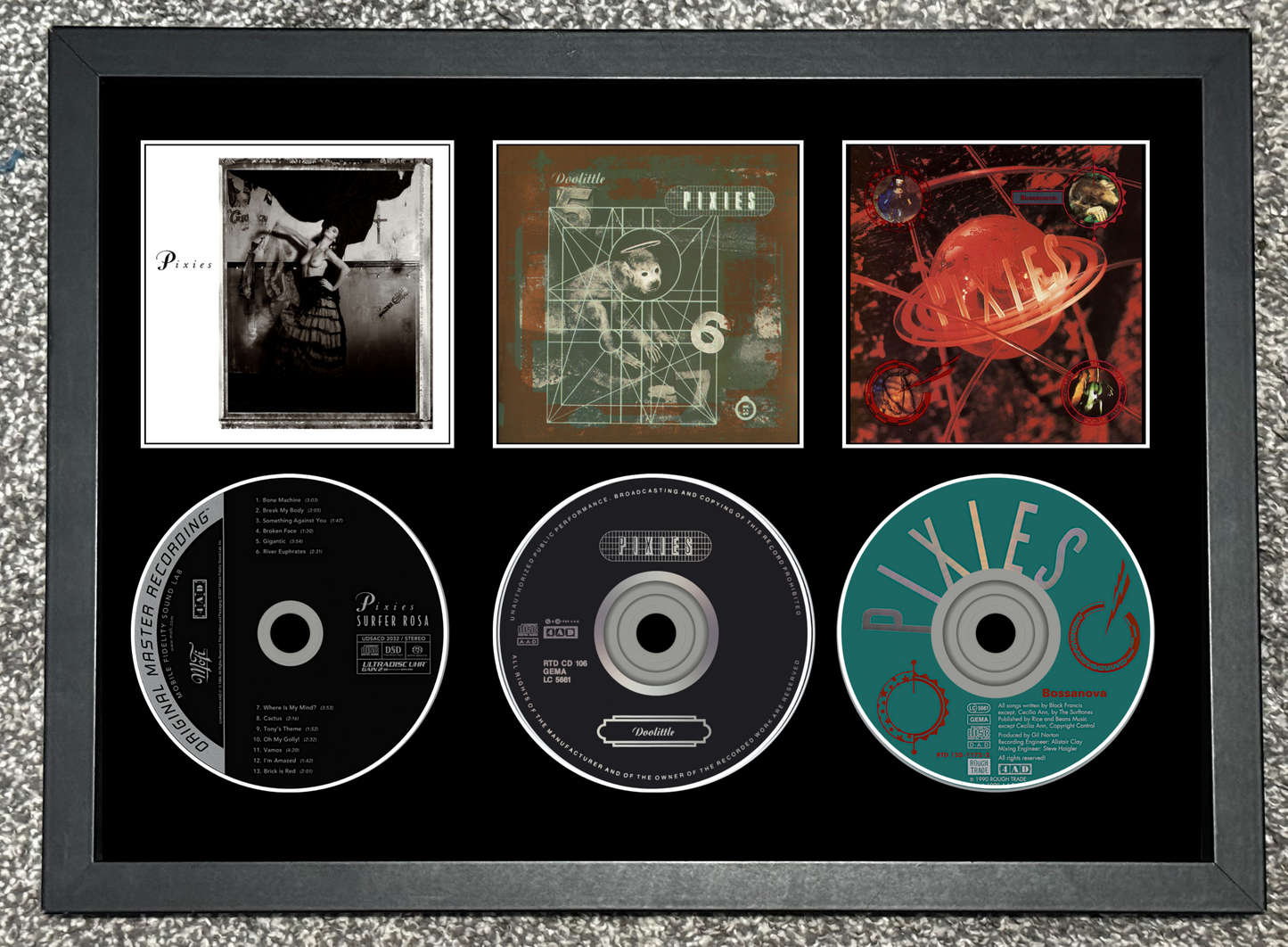Framed display of music album covers and CDs with a black border.