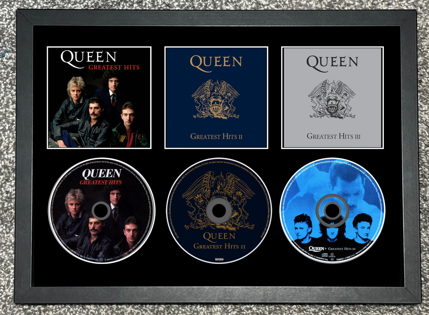 Framed Queen Greatest Hits album collection with five CDs and cover images.
