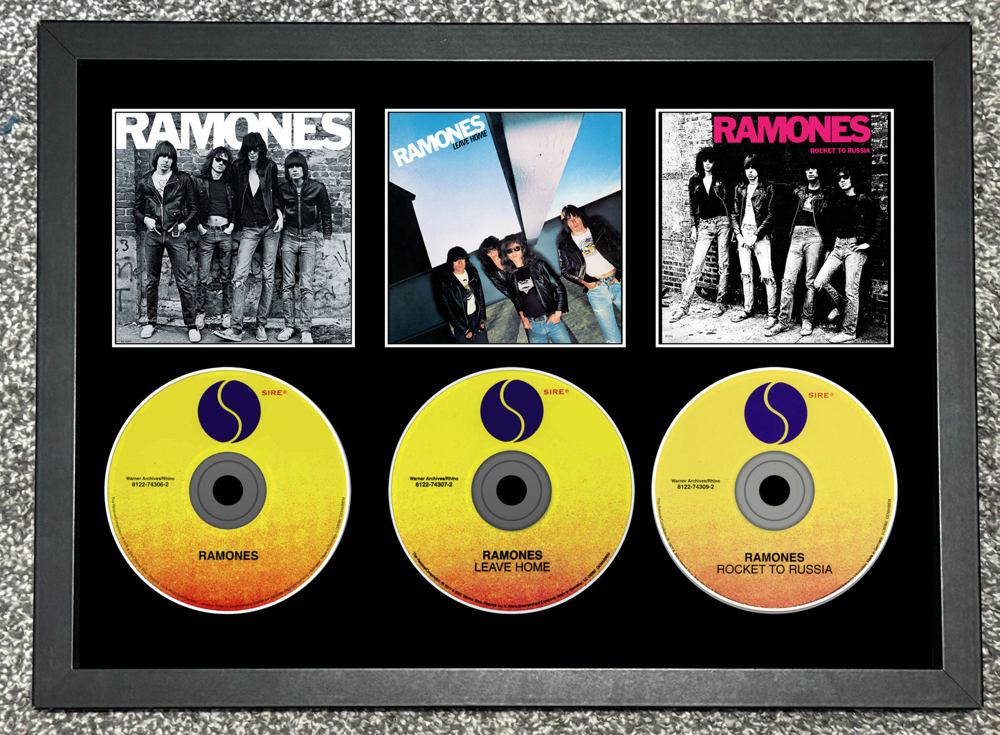 Framed display of Ramones album covers and CDs on a textured surface