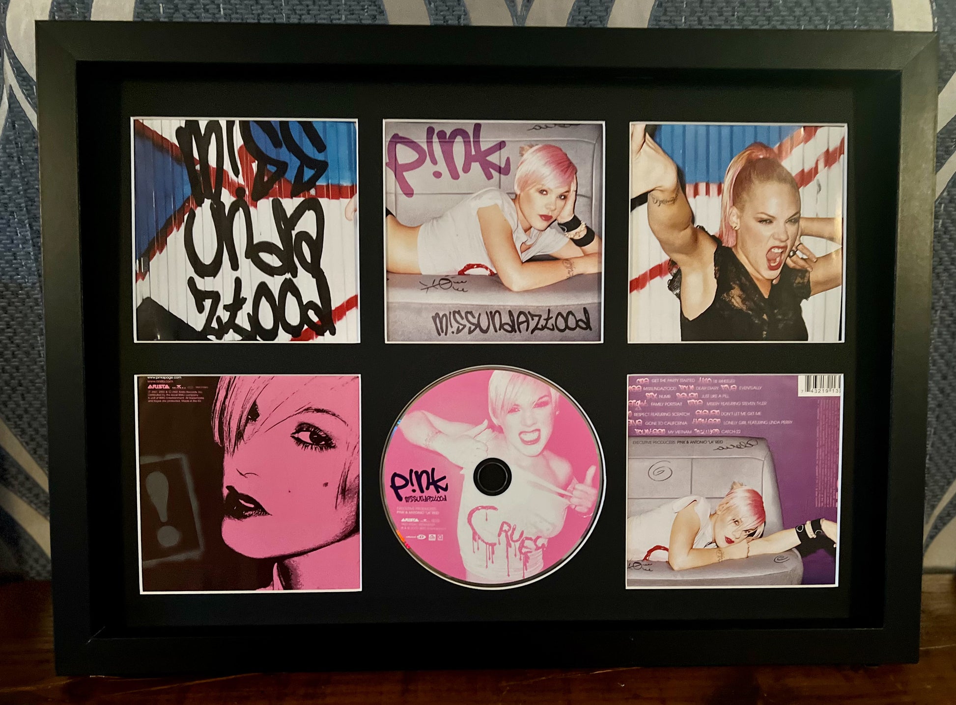 Framed collection of Pink music album covers and a CD