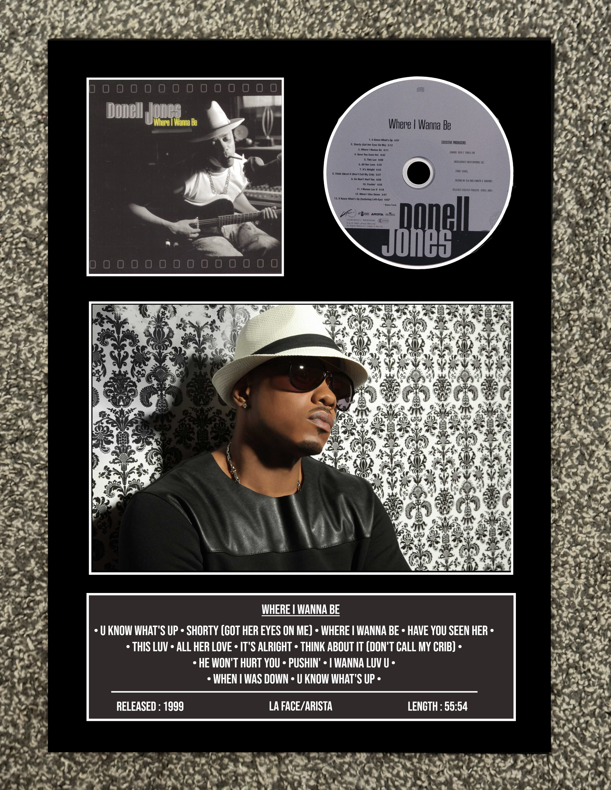 Framed album cover with a portrait of a person wearing a hat and sunglasses, a CD, and album tracklist.