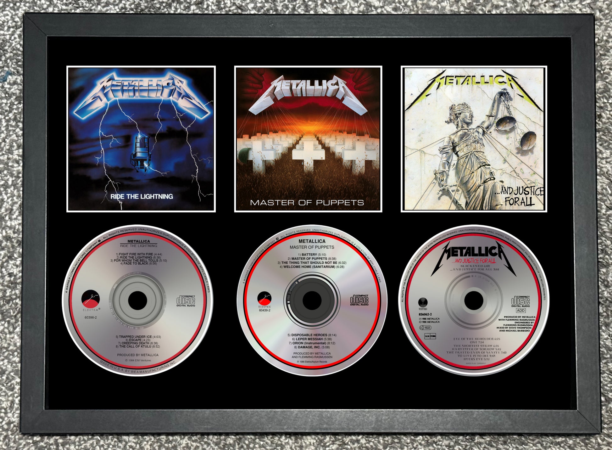Framed Metallica album covers and CDs on a textured surface