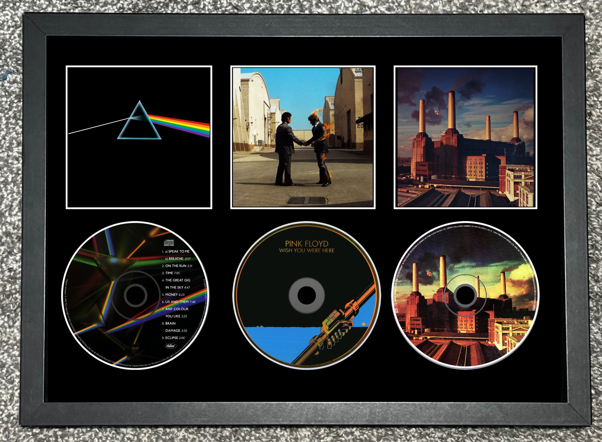 Framed Pink Floyd album covers and CDs on a textured surface