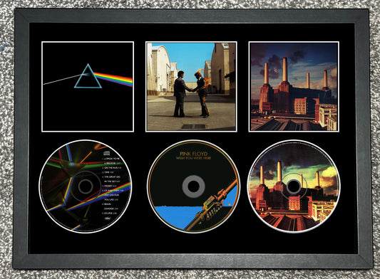 Framed Pink Floyd album covers and CDs on a textured surface