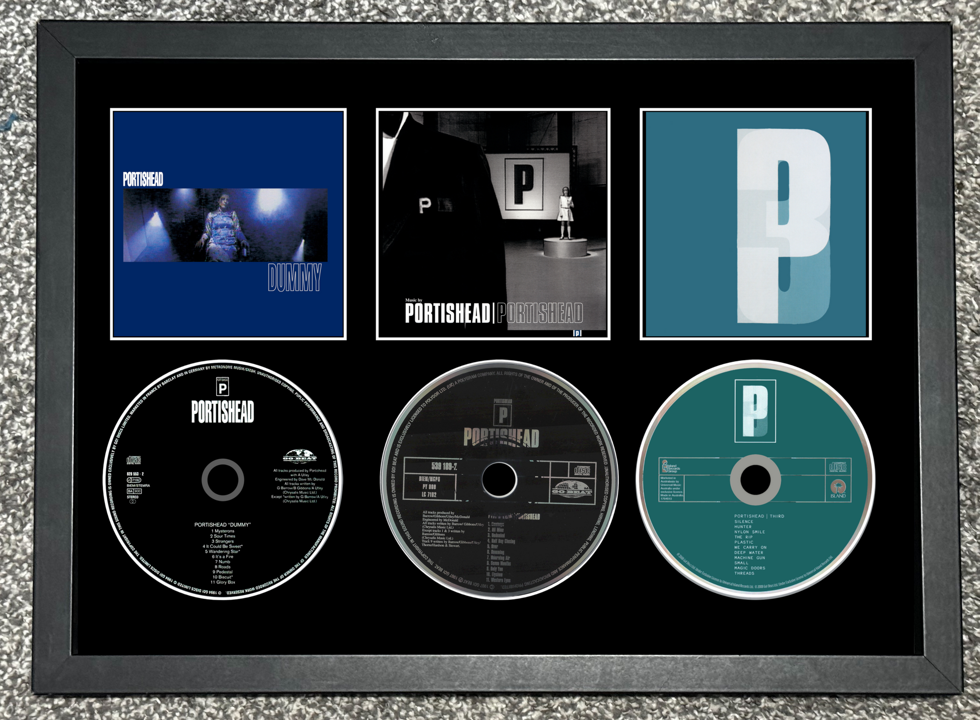 Framed Portishead music album cover and CDs on a textured gray background