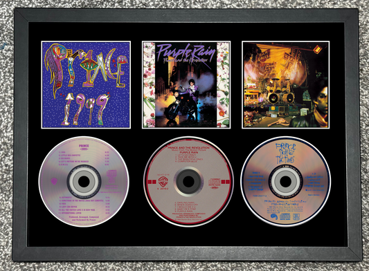 Framed display of Prince albums and CDs with colorful cover art.