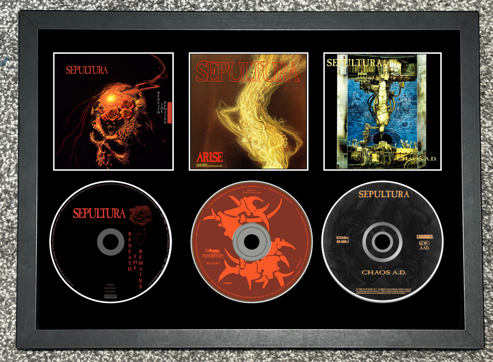 Framed Sepultura album covers and CDs on a textured surface