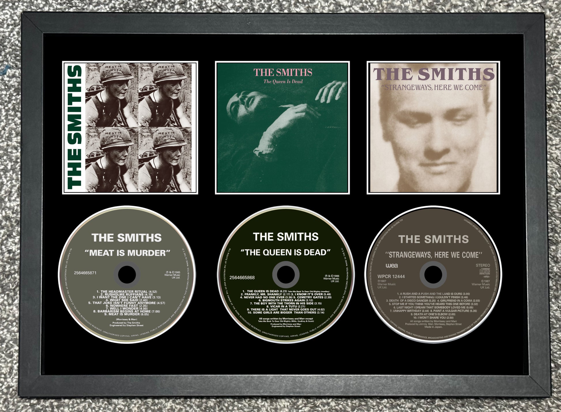 Framed album covers and CDs of The Smiths on a textured gray background