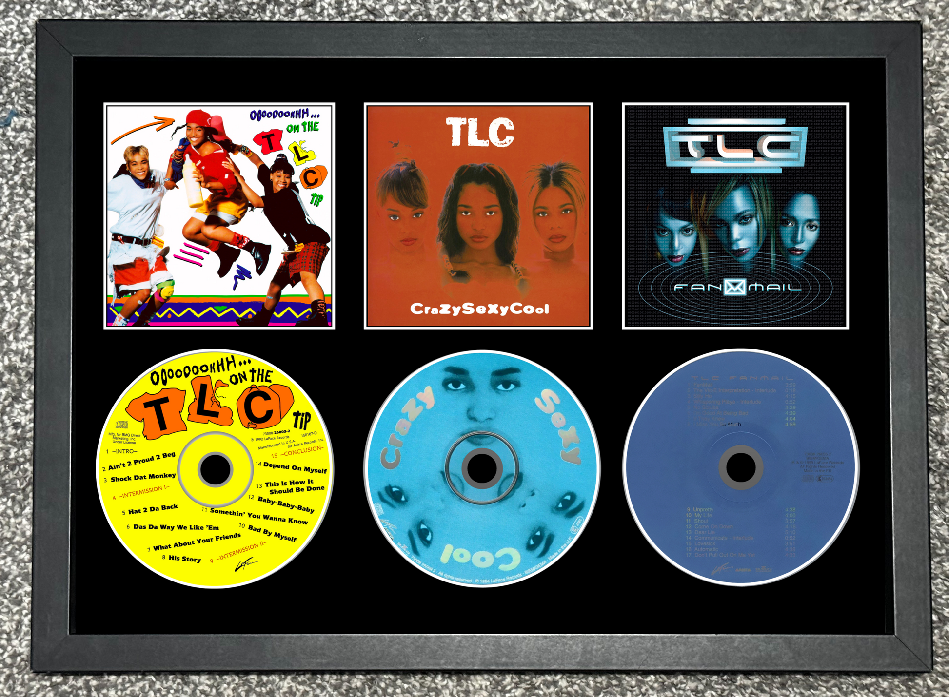 Framed display of TLC music album covers and CDs on a textured gray background